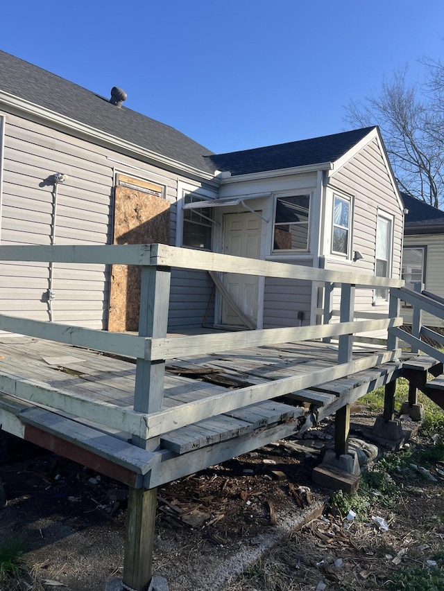 view of side of home with a deck and a shingled roof