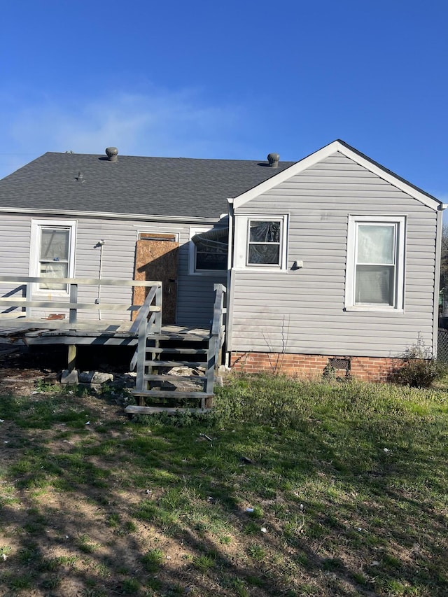 back of property featuring a yard, a deck, and a shingled roof