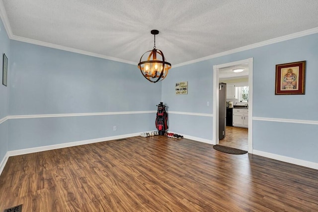 unfurnished room featuring wood finished floors, baseboards, ornamental molding, a textured ceiling, and a chandelier