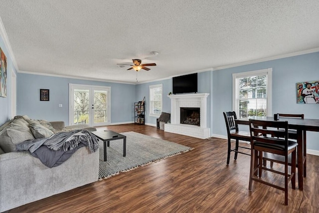 living area featuring ornamental molding, a fireplace, dark wood-style flooring, and ceiling fan