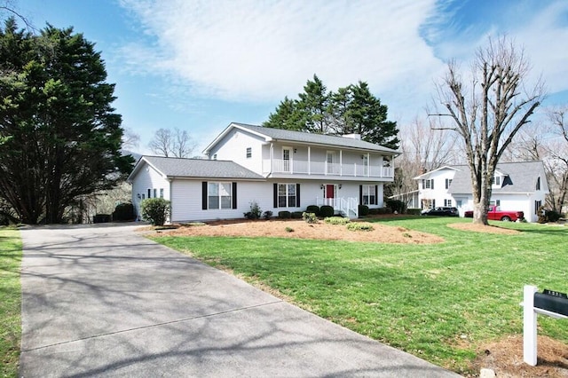 view of front of house with a balcony, driveway, and a front yard