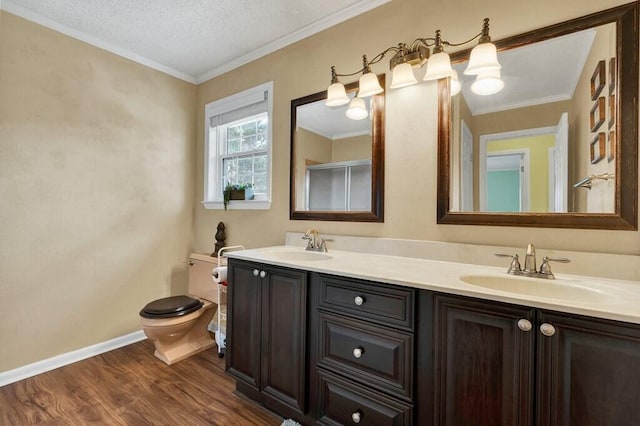 full bathroom with crown molding, toilet, wood finished floors, and a sink