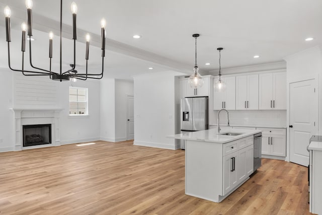 kitchen with a notable chandelier, a sink, stainless steel appliances, white cabinets, and decorative backsplash