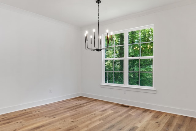 unfurnished dining area with light wood-type flooring, visible vents, crown molding, baseboards, and a chandelier