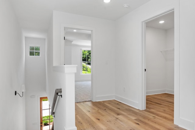 hall featuring light wood finished floors, an upstairs landing, recessed lighting, and baseboards