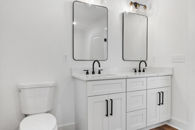 full bath featuring double vanity, toilet, baseboards, and a sink