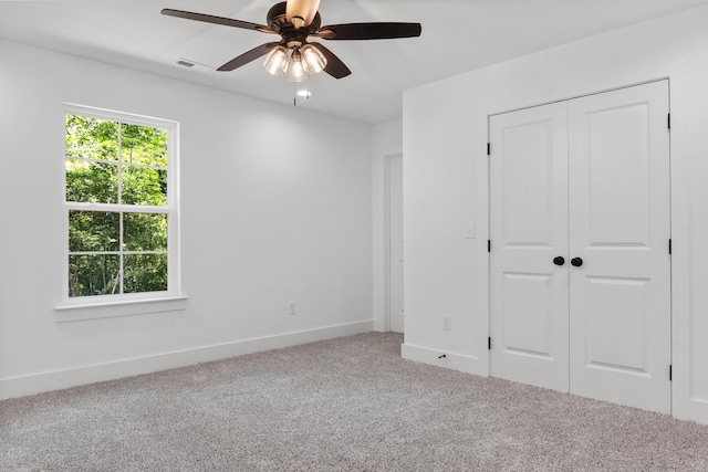 unfurnished bedroom featuring carpet, visible vents, baseboards, ceiling fan, and a closet