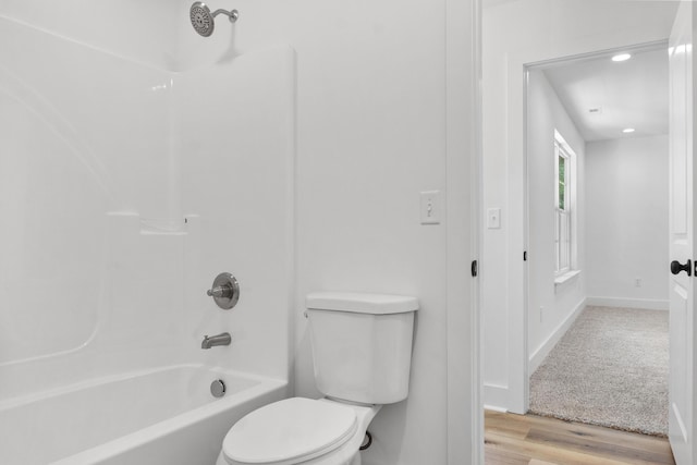 bathroom with baseboards, toilet, bathtub / shower combination, and wood finished floors