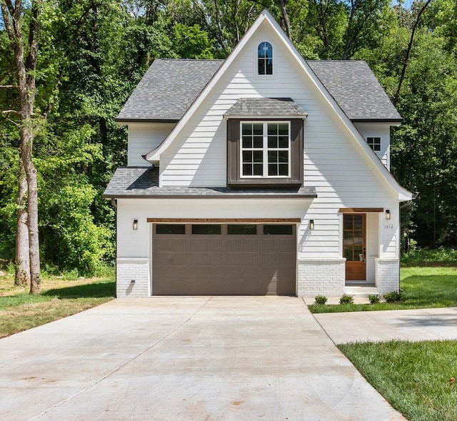 view of front of home with concrete driveway, an attached garage, brick siding, and a shingled roof