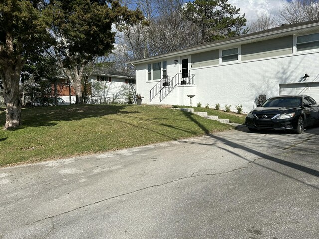 ranch-style home featuring aphalt driveway, brick siding, and a front lawn