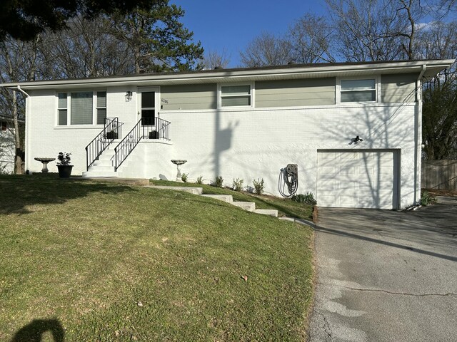 view of front of property with brick siding, an attached garage, aphalt driveway, and a front yard