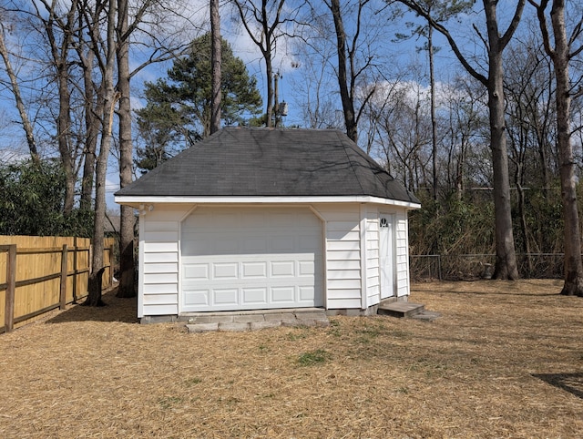 detached garage featuring a storage shed and fence