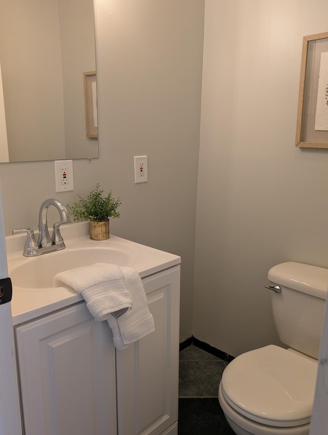 bathroom featuring toilet, vanity, and baseboards