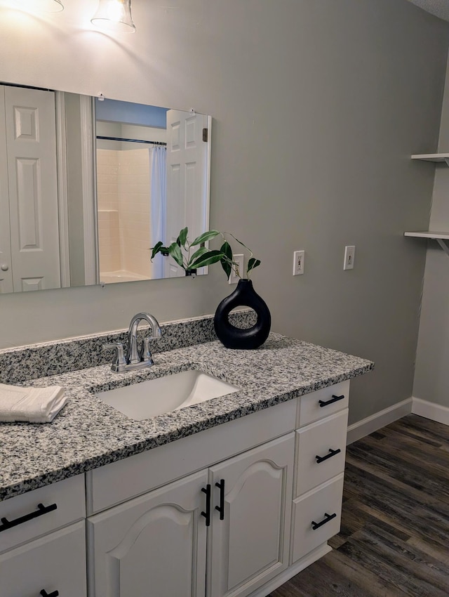 bathroom featuring vanity, curtained shower, wood finished floors, and baseboards