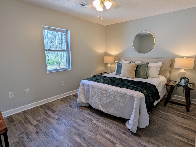 bedroom with visible vents, a textured ceiling, baseboards, and wood finished floors