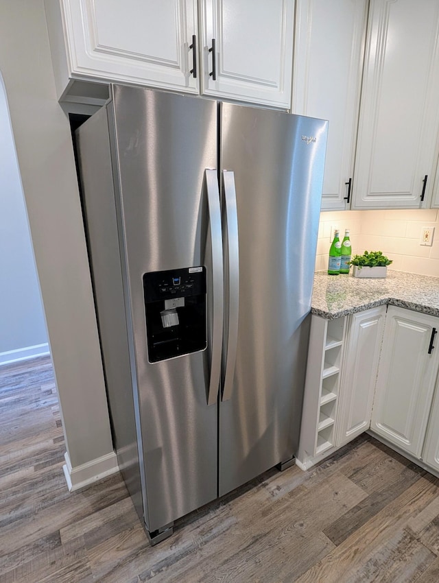 kitchen featuring tasteful backsplash, white cabinets, stainless steel refrigerator with ice dispenser, and wood finished floors