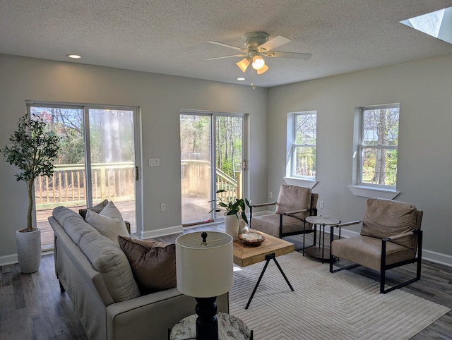 living room with a textured ceiling, wood finished floors, baseboards, and ceiling fan