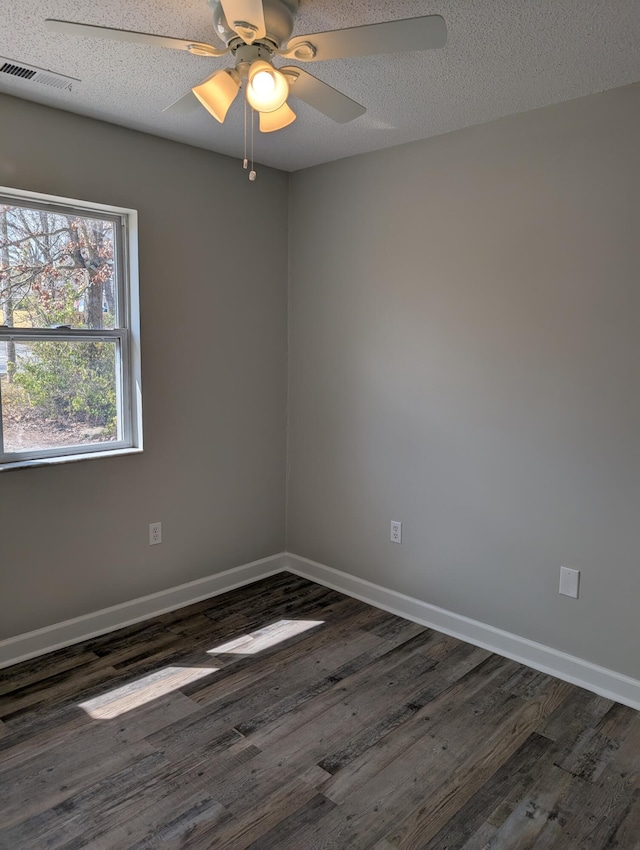 unfurnished room featuring visible vents, baseboards, a textured ceiling, and dark wood-style flooring