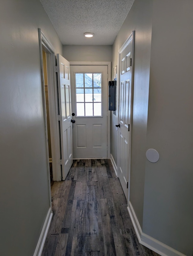 entryway with baseboards, a textured ceiling, and dark wood-style flooring