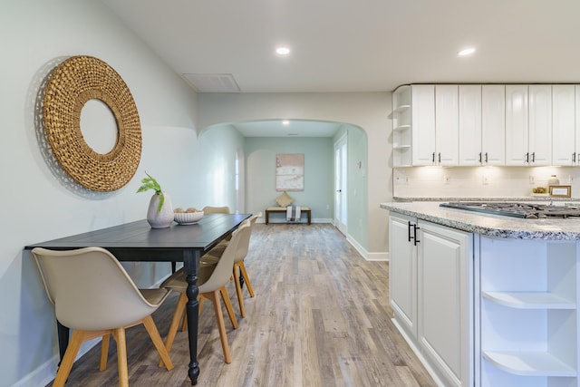 kitchen featuring open shelves, arched walkways, white cabinets, and stainless steel gas cooktop