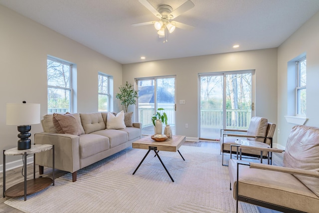 living area with recessed lighting, a ceiling fan, baseboards, and light wood finished floors