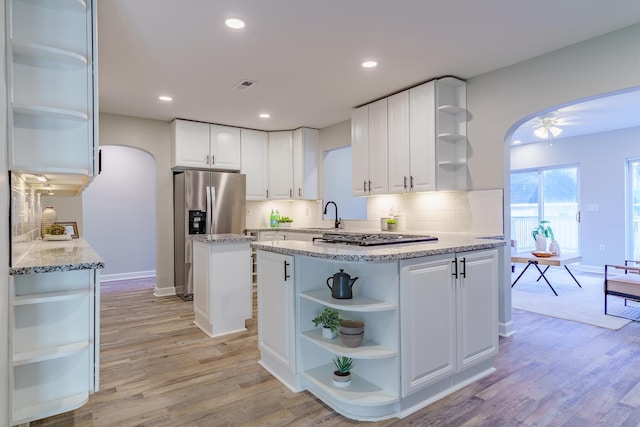 kitchen featuring open shelves, a ceiling fan, arched walkways, and stainless steel appliances