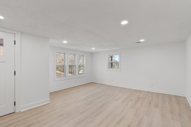 basement featuring light wood finished floors, recessed lighting, a textured ceiling, and baseboards