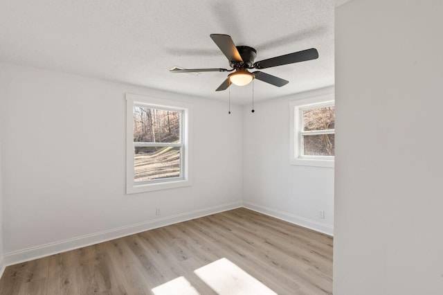 unfurnished room featuring a ceiling fan, baseboards, light wood finished floors, and a textured ceiling