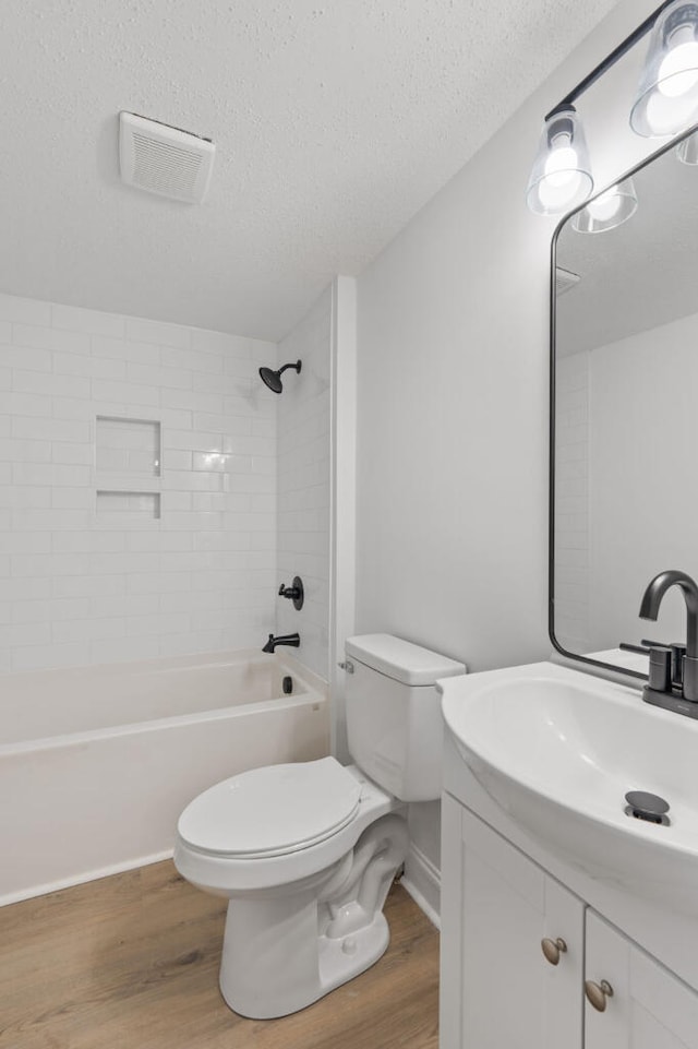 full bathroom with visible vents, shower / washtub combination, toilet, wood finished floors, and a textured ceiling