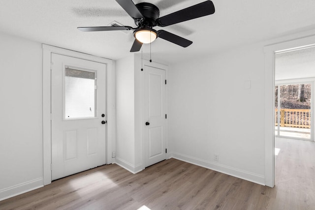 interior space featuring light wood finished floors, ceiling fan, a textured ceiling, and baseboards