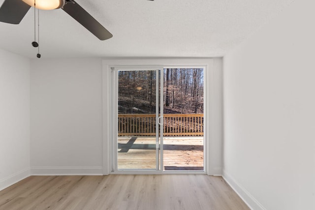 unfurnished room featuring light wood finished floors, a textured ceiling, a ceiling fan, and baseboards