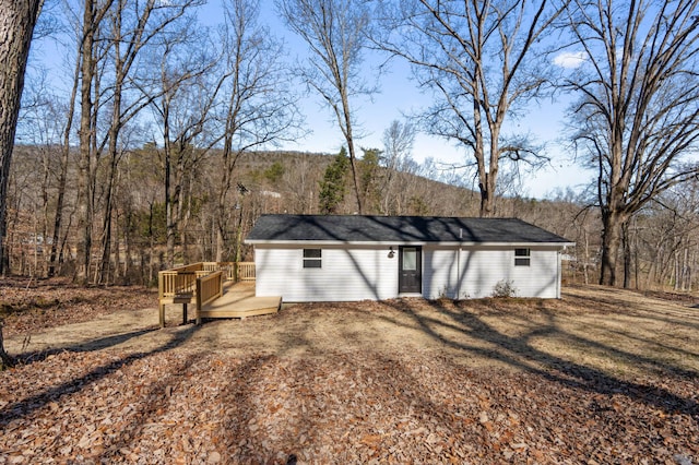 rear view of house featuring a wooded view and a deck