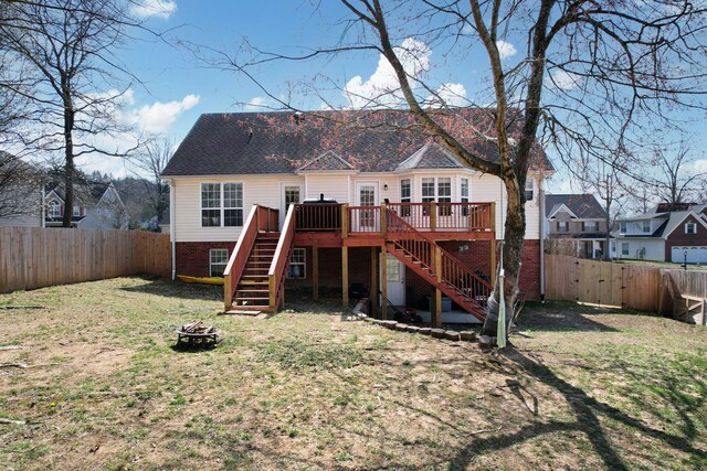 back of house with an outdoor fire pit, a fenced backyard, stairs, a deck, and a lawn