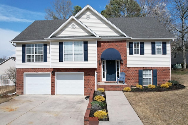 split foyer home featuring a garage, brick siding, and driveway