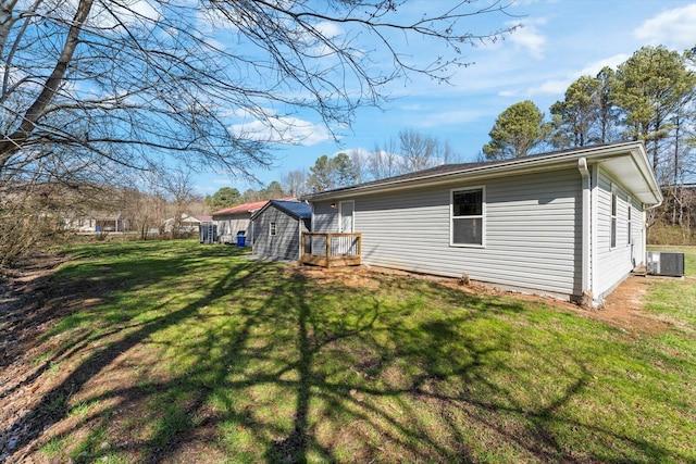 rear view of property featuring central air condition unit, a lawn, a storage unit, and an outdoor structure