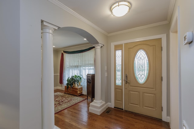 foyer entrance with dark wood finished floors, decorative columns, arched walkways, and ornamental molding