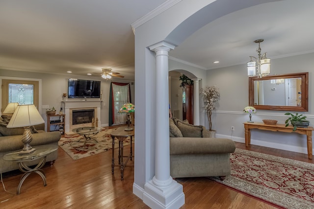 living area featuring decorative columns, a fireplace, arched walkways, and ornamental molding