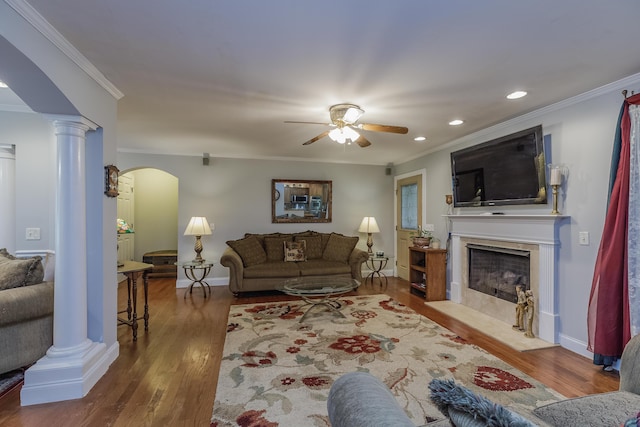 living room with wood finished floors, a ceiling fan, ornate columns, arched walkways, and a high end fireplace