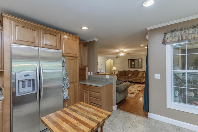 kitchen with light tile patterned floors, open floor plan, stainless steel refrigerator with ice dispenser, and crown molding