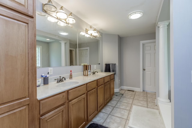 full bath with a sink, decorative columns, baseboards, and double vanity