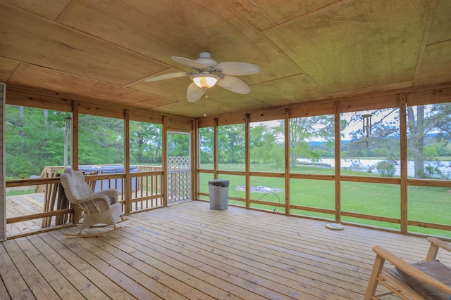 unfurnished sunroom with wood ceiling, a ceiling fan, and a water view