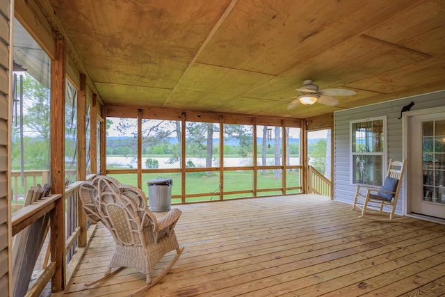 unfurnished sunroom featuring wood ceiling and a ceiling fan