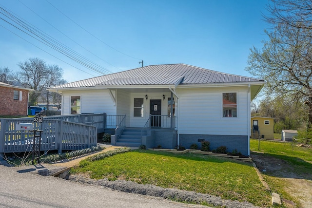 view of front of house with metal roof, covered porch, a front lawn, and fence