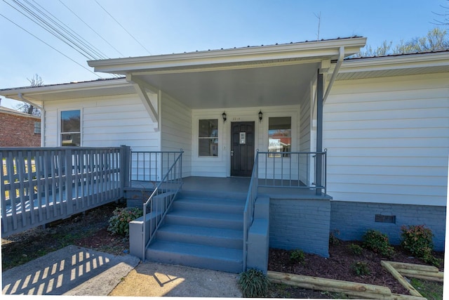 view of exterior entry with a porch and crawl space