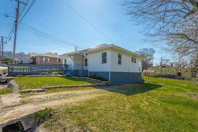 view of property exterior featuring a yard, covered porch, and fence