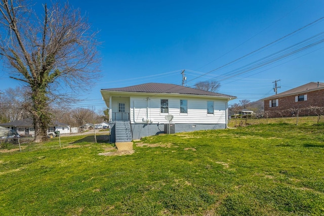 back of house featuring a lawn, metal roof, and fence