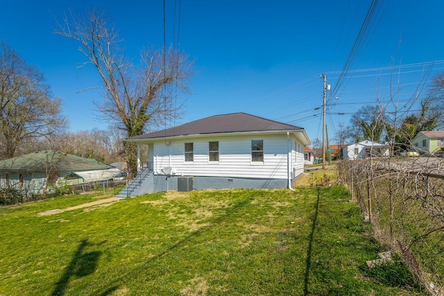 rear view of property with a lawn, cooling unit, metal roof, and fence