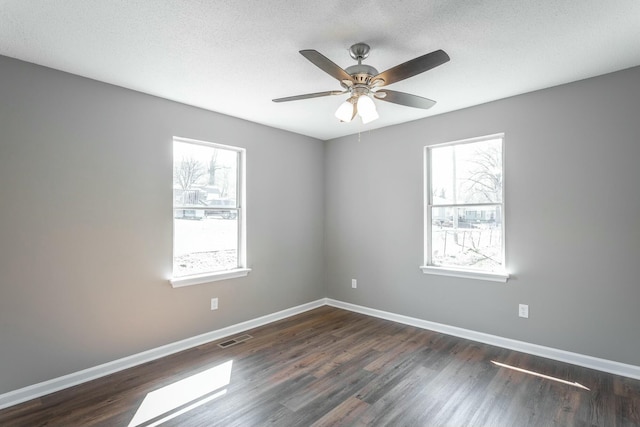 spare room featuring visible vents, baseboards, dark wood-type flooring, and a textured ceiling