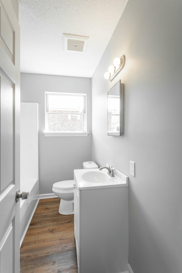 bathroom featuring toilet, a textured ceiling, wood finished floors, baseboards, and vanity