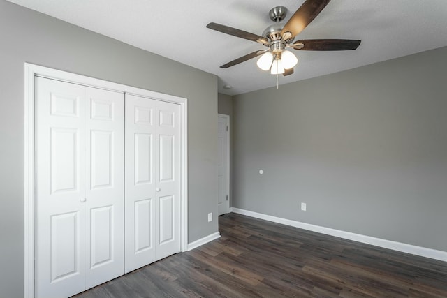 unfurnished bedroom with a closet, baseboards, dark wood finished floors, and a ceiling fan